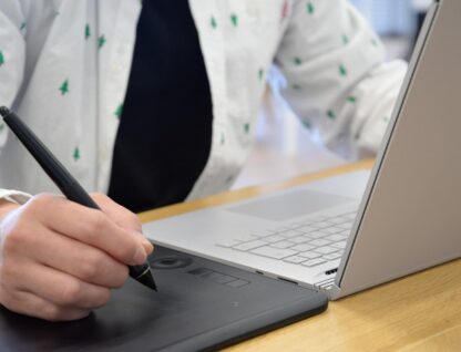 Imagem de pessoa fazendo uso de um computador e uma mesa digitalizadora