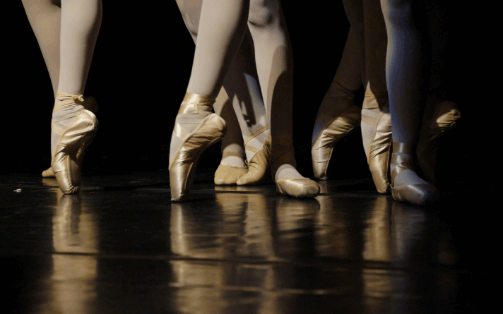 Imagem mostra pés de diversas bailarinas, em palco, dançando