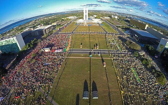 Imagem aérea da frente do Congresso Nacional, em Brasília, no dia da votação de impeachment de Dilma Rousseff; à esquerda, grande grupo de pessoas de vermelho e, à direita, grande grupo de pessoas vestidas de verde e amarelo, separadas por um canteiro central
