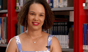 Mulher negra com cabelos crespos acima dos ombros, usa blusa azul com elementos brancos