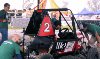 Três estudantes homens confere os detalhes do carro construído pela equipe