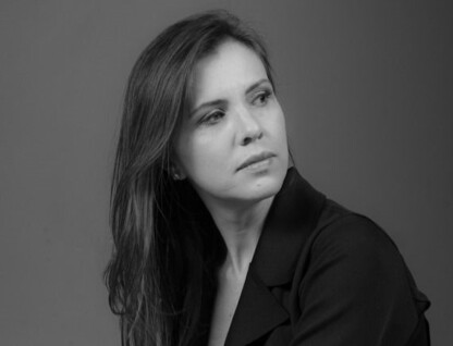 Foto em preto e branco. Carla Pedrosa, vestida com uma blazer preto, olha para o lado.